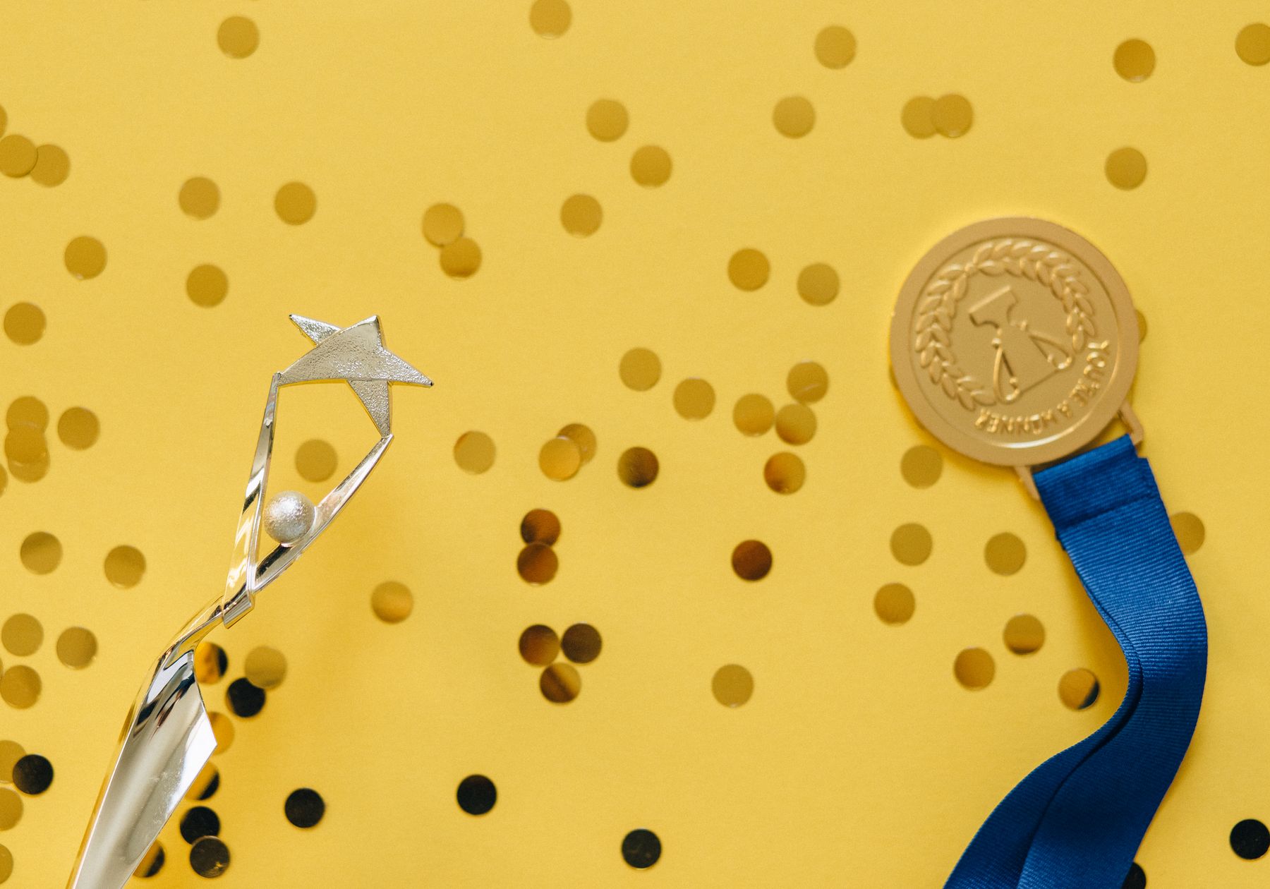 A silver trophy and medal surrounded by celebratory confetti