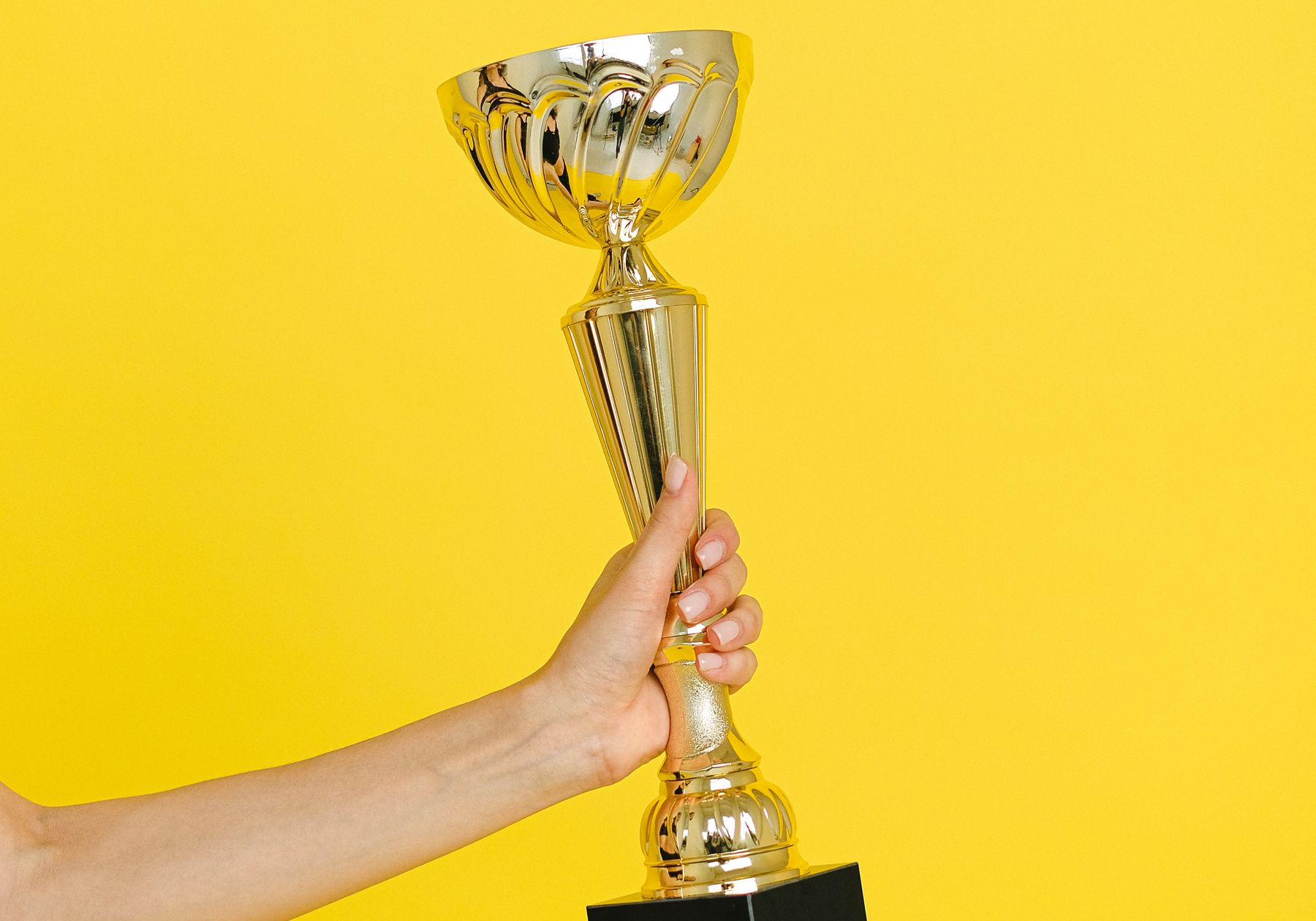 A gold trophy held against a bright backdrop