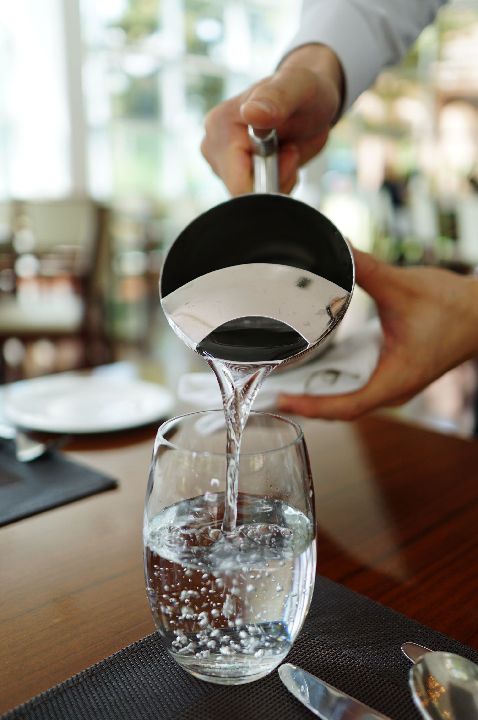 Fresh water being poured into a glass at a restaurant table