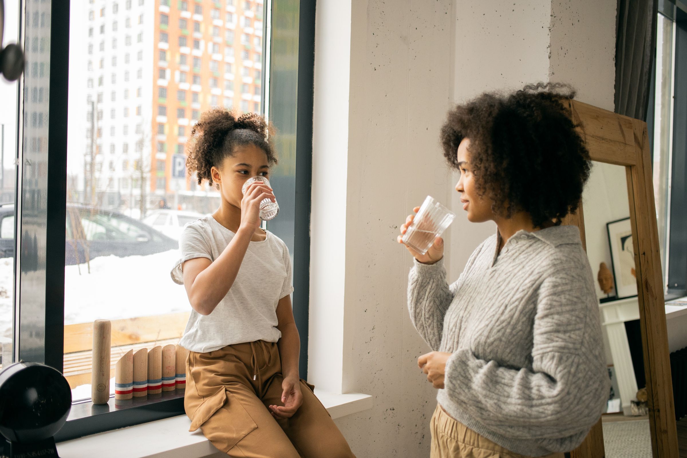 Mother and daughter enjoying glasses of water together at home